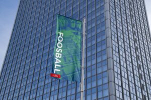 Waving banner that says Foosball, in front of a skyscraper