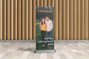 A standing sign located in a mall with a happy couple on it